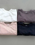 Vier Boxy-Longsleeves in Ivory, Rosé, braun und schwarz, zusammengelegt
