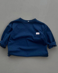 Dunkelblaues Longsleeve-Tee mit lockerer Passform und kleinem Label auf der Brust.