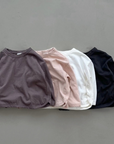 Vier Longsleeves mit Boxy-Schnitt in verschiedenen Farben – Ivory, Rosé, braun und schwarz.