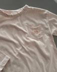 Nahaufnahme des weichen Stoffes und Labels auf der Brust des cremefarbenen Longsleeve-Tees.