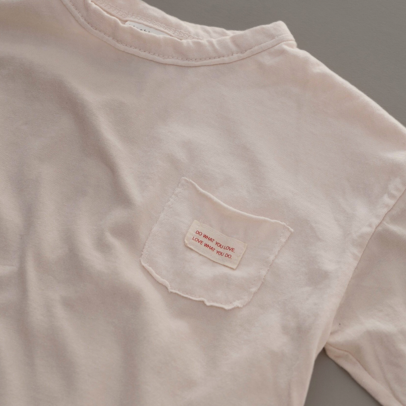 Nahaufnahme des weichen Boxy Longsleeve  und Labels auf der Brust des cremefarbenen Longsleeve-Tees.