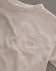 Nahaufnahme des weichen Boxy Longsleeve  und Labels auf der Brust des cremefarbenen Longsleeve-Tees.