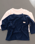 Cremefarbenes und dunkelblaues Longsleeve-Tee – locker geschnitten mit kleiner Brusttasche.