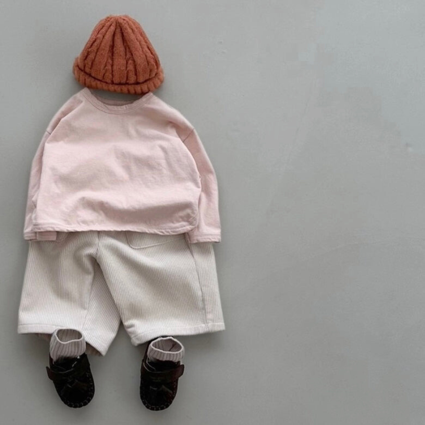 Roséfarbenes Boxy-Longsleeve kombiniert mit heller Mütze, beiger Hose und dunklen Schuhen.