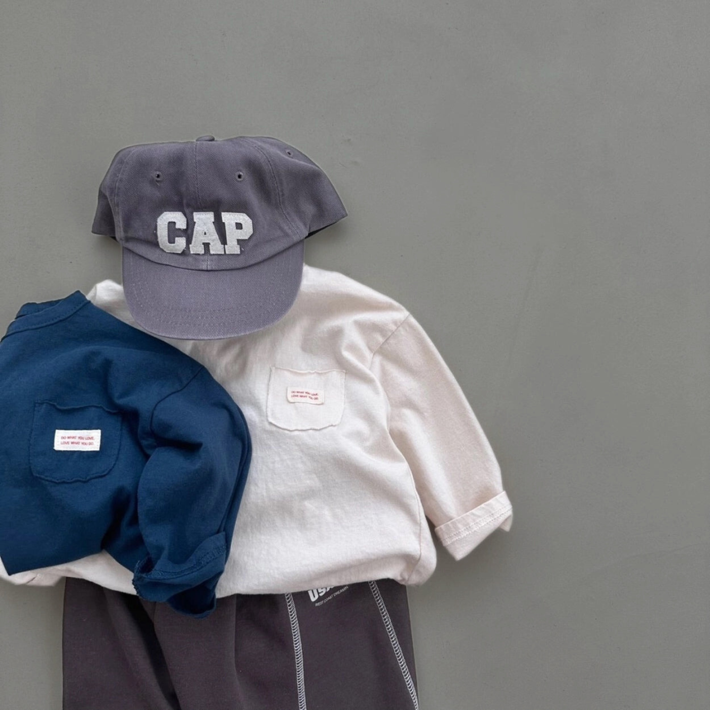 Cremefarbenes und dunkelblaues  Longsleeve-Tee kombiniert mit dunkler Hose, grauer Cap