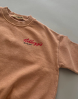 Kleiner roter „Kellogg’s“ Print auf der Brust des beigen Sweatshirts.
