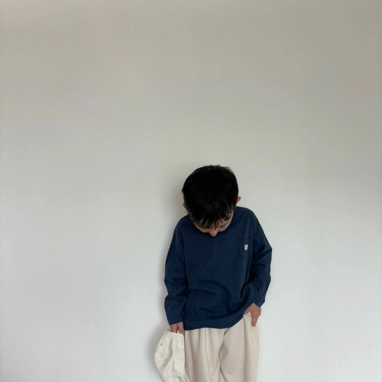 Kind trägt dunkelblaues Longsleeve mit beigefarbenen Hose