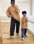 Spiegelbild von Kind und Erwachsenem im beigen „Frosted Flakes“ Sweatshirt – „Kellogg’s“ Schriftzug vorne, großer Print mit Tony der Tiger auf dem Rücken.