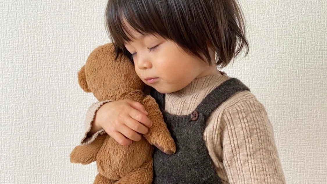 Kleinkind mit Teddy im Arm Little Foxx