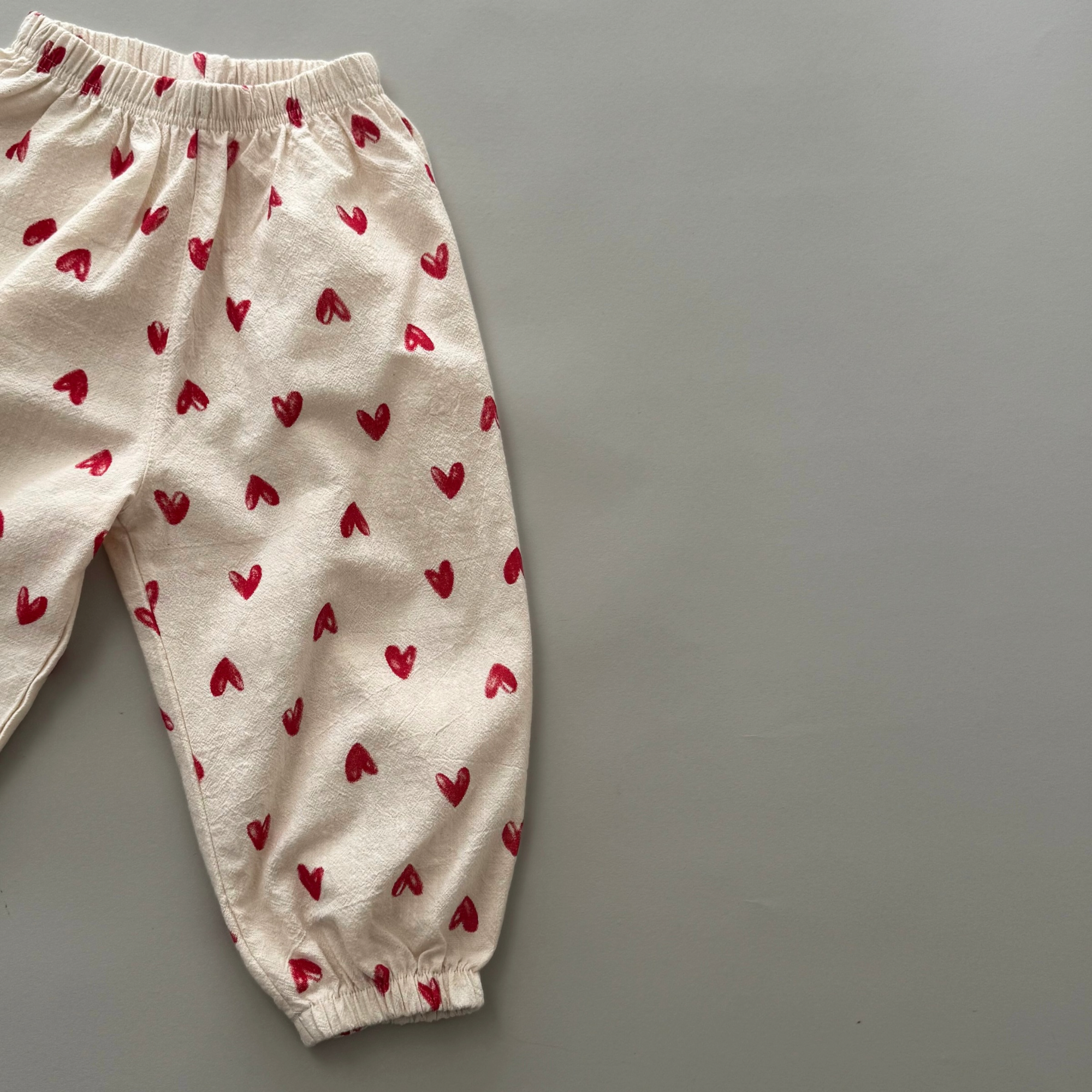 Cremefarbene Kinderhose mit Herzmuster – weicher Stoff, elastischer Bund.