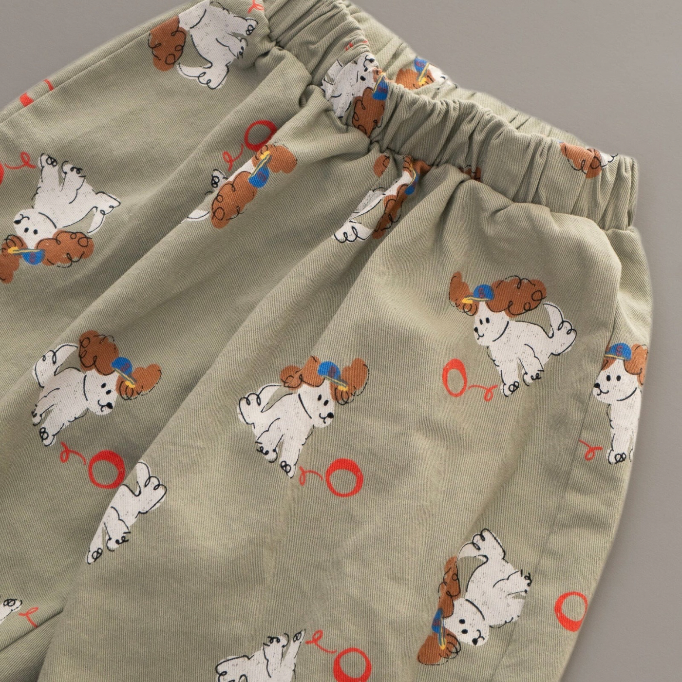 Nahaufnahme des elastischen Bundes und des weichen Stoffs der khakifarbenen Hose mit Hundeprint.