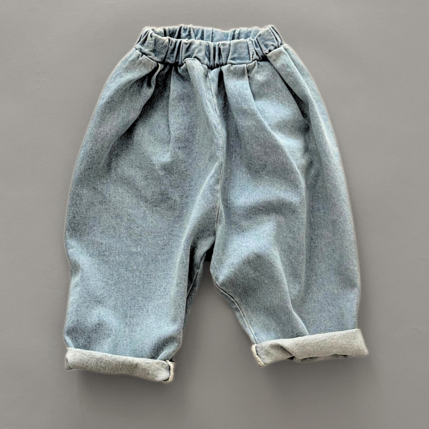 Hellblaue Kinderjeans mit hochgekrempelten Hosenbeinen für einen lässigen Look.