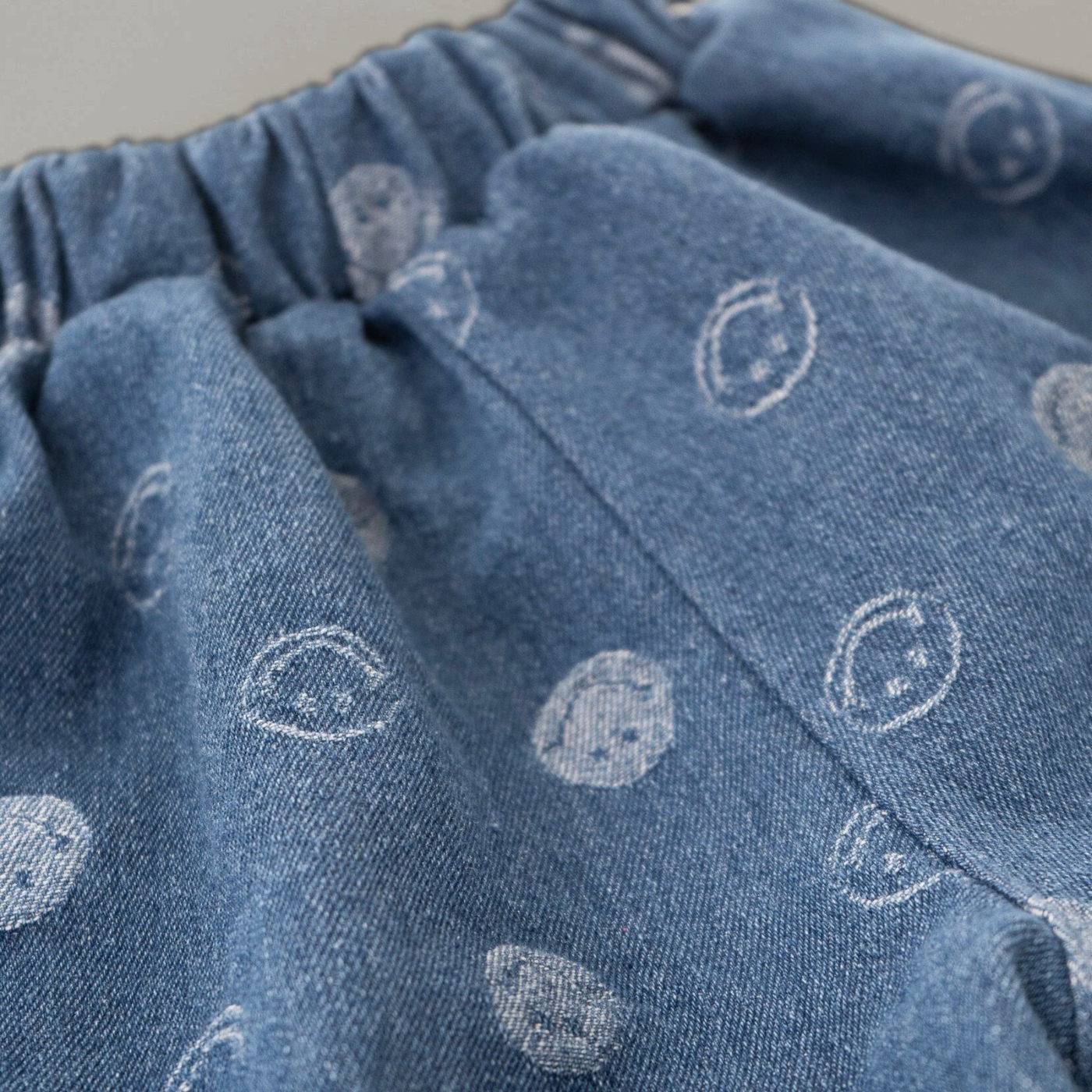 Nahaufnahme des Smiley-Muster auf der blauen Jeans – dezentes, verspieltes Design.