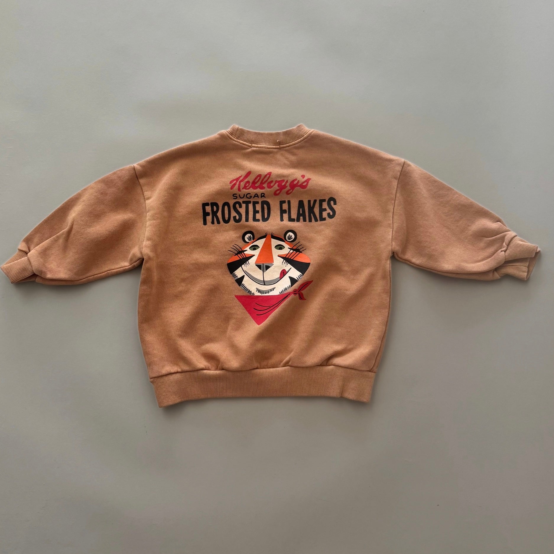 Beiges Sweatshirt mit großem „Frosted Flakes“ Print auf dem Rücken – zeigt Tony den Tiger mit einer Schüssel Cornflakes und der Aufschrift „Frosted Flakes“.