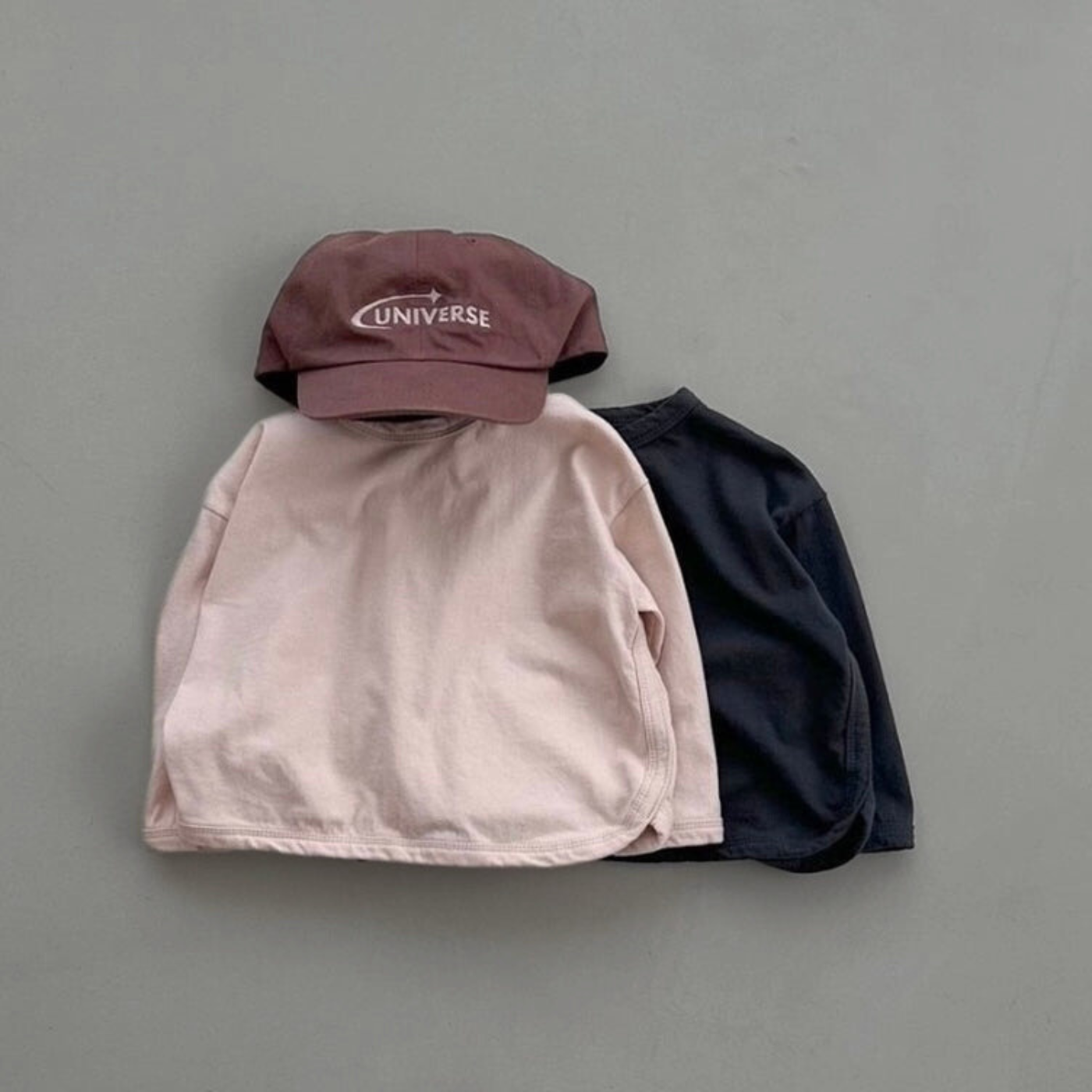 Roséfarbenes und schwarzes Longsleeve mit Boxy-Schnitt kombiniert mit Cap 