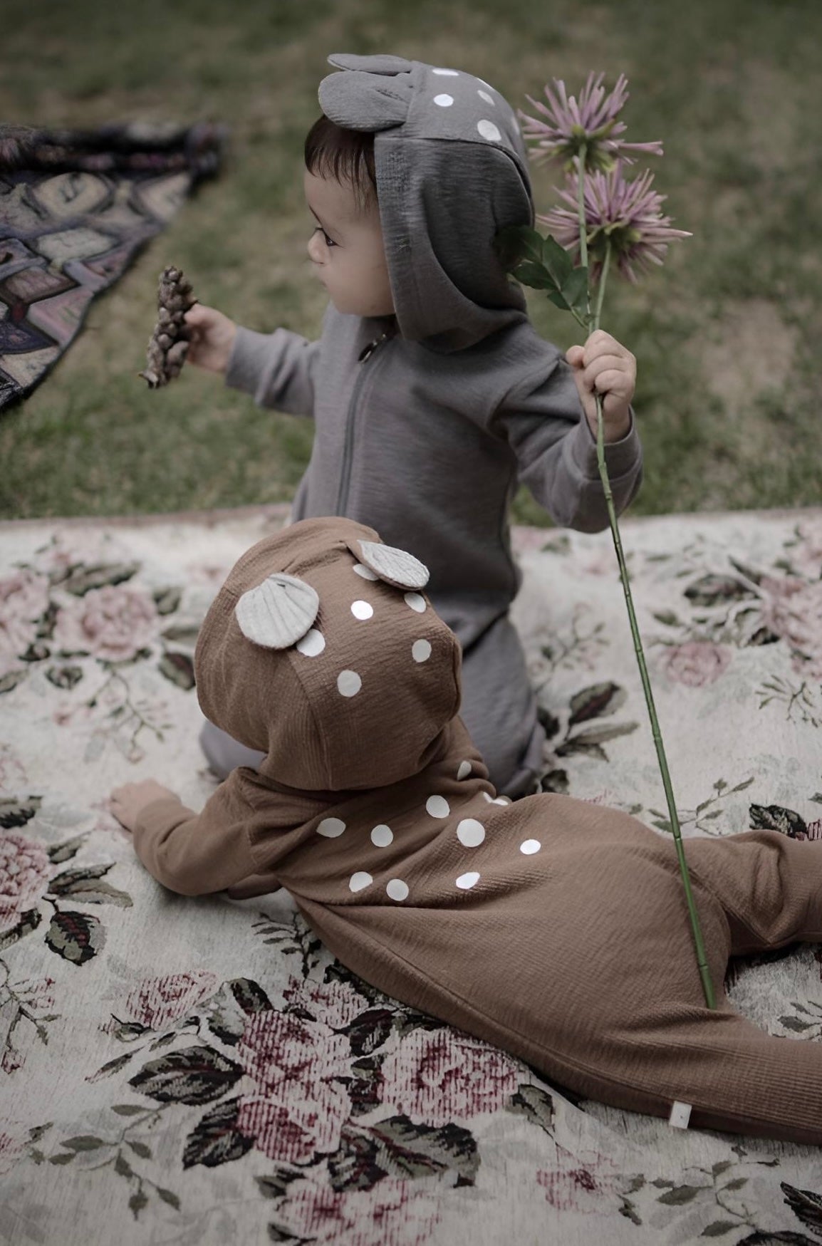 Baby in a Bambi onesie holding flowers